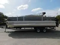 Slide: The Image of 2024 Sun Tracker Fishin' Barge 22 XP3 pontoon boat on a trailer under a blue sky. - 11