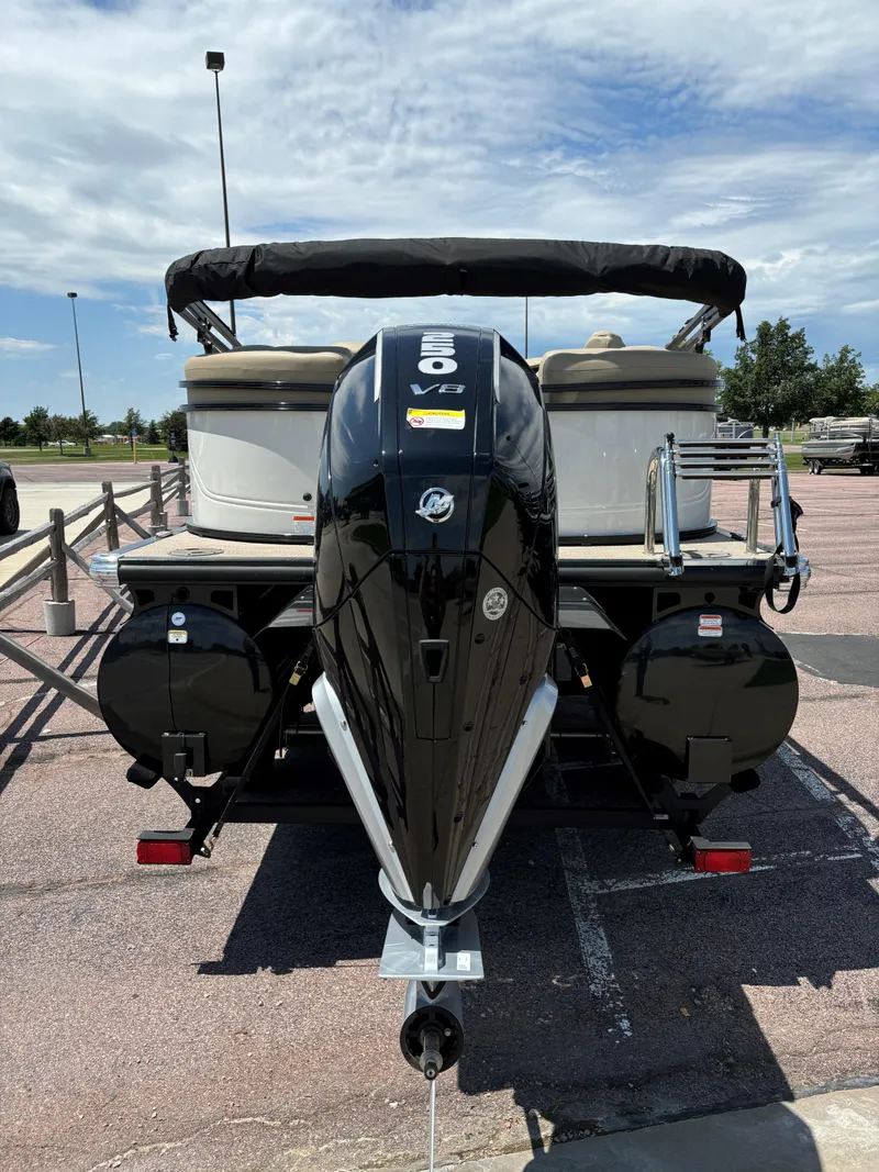 Slide: The Image of 2024 Regency 230 DL3 pontoon boat with outboard motor, parked on a trailer. - 4