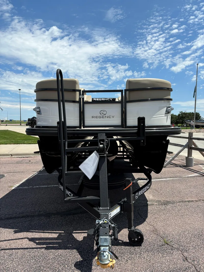 Slide: The Image of 2024 Regency 230 DL3 pontoon boat on trailer, parked under a clear sky. - 5