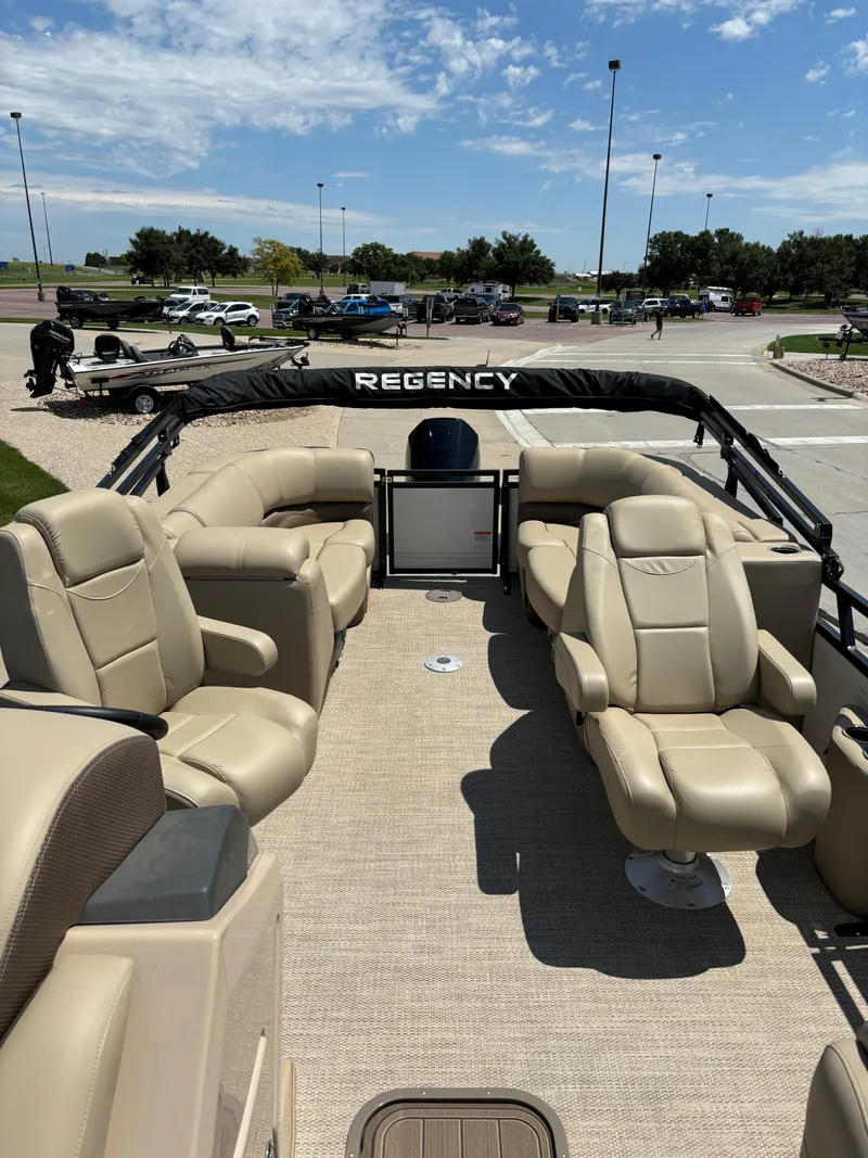 Slide: The Image of 2024 Regency 230 DL3 pontoon boat with beige seating in a parking lot. - 9