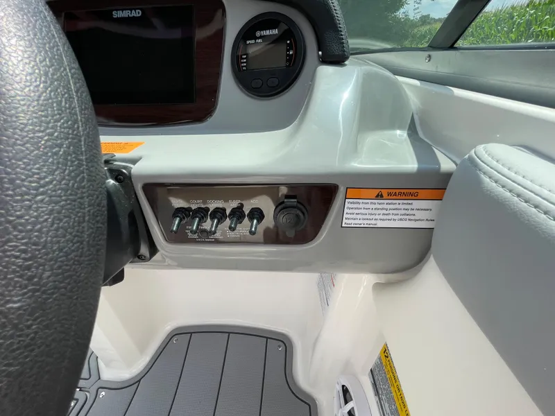 Slide: The Image of 2024 Chaparral 21 SSi OB boat dashboard with control switches and warning labels. - 26