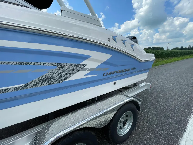 Slide: The Image of 2024 Chaparral 21 SSi OB boat on a trailer, side view with blue and white design. - 4