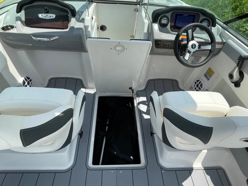 Slide: The Image of 2024 Chaparral 21 SSi OB boat interior with open storage compartment and dual captain seats. - 43