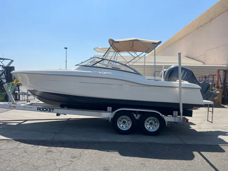 Slide: The Image of 2019 Scout 210 Dorado boat on a Rocket trailer, parked outdoors. - 2