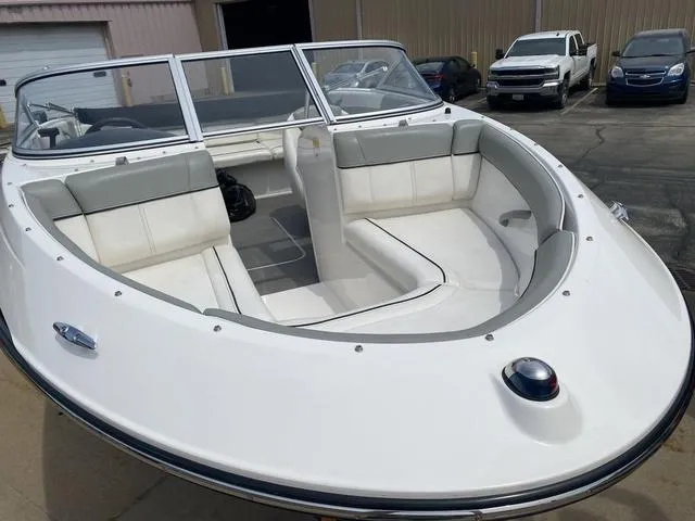 Slide: The Image of 2012 Bayliner 195 Bowrider boat with white and gray interior, parked in a lot. - 3