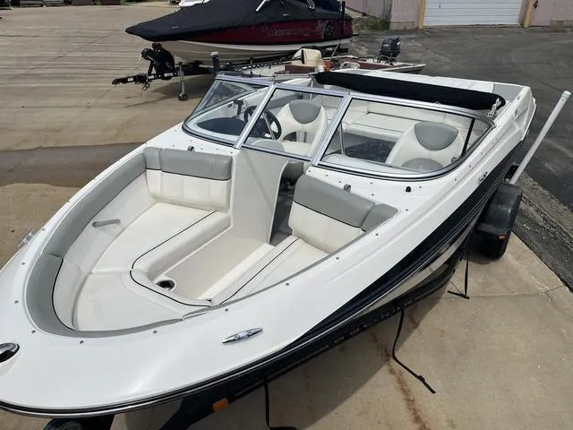 Slide: The Image of 2012 Bayliner 195 Bowrider boat with white and gray interior, parked on a trailer. - 4