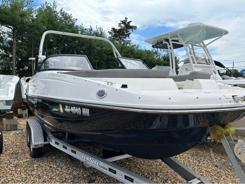 Slide: The Image of 2016 Bayliner 215 Deck Boat on trailer, parked on gravel lot. - 2