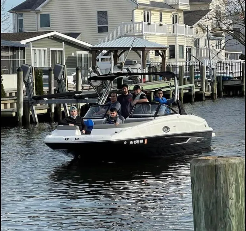 Slide: The Image of 2016 Bayliner 215 Deck Boat with passengers cruising near waterfront homes. - 7