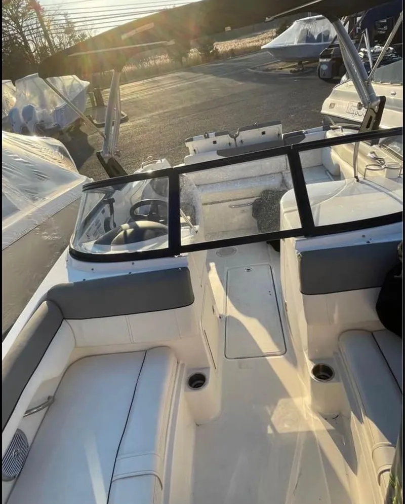 Slide: The Image of 2016 Bayliner 215 Deck Boat interior with seating and steering wheel, parked outdoors. - 9