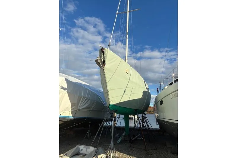 Slide: The Image of 1984 Pearson 34 sailboat on stands, covered, under a blue sky. - 3
