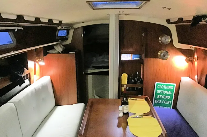 Slide: The Image of Cozy interior of a 1984 Pearson 34 sailboat with dining setup and ambient lighting. - 6