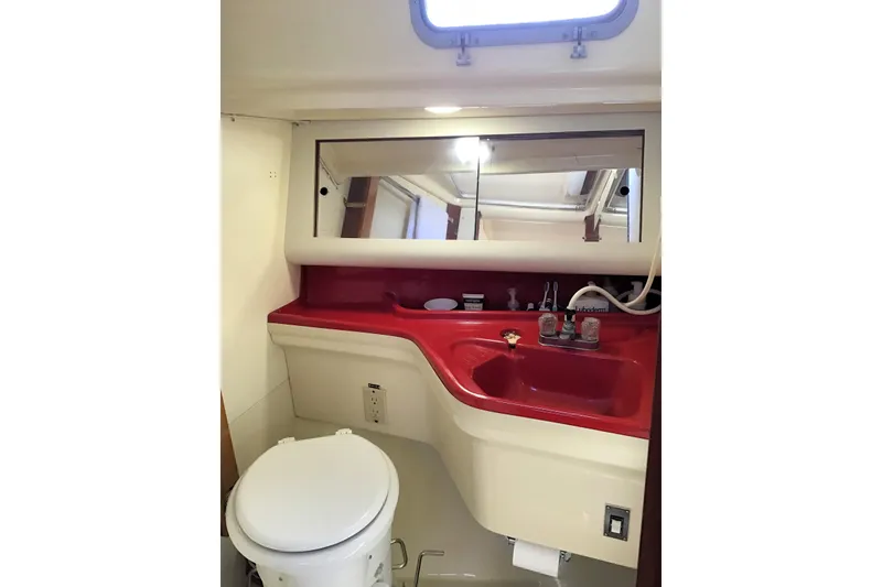 Slide: The Image of 1984 Pearson 34 yacht bathroom with red sink, mirror, and toilet. - 9