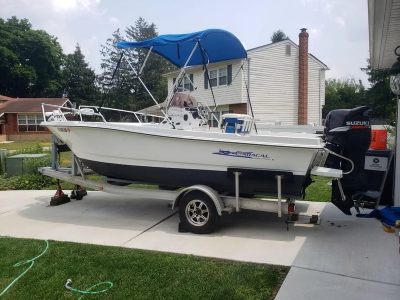 Slide: The Image of White 2008 Caracal 180 boat on trailer with blue canopy, parked in residential driveway. - 0