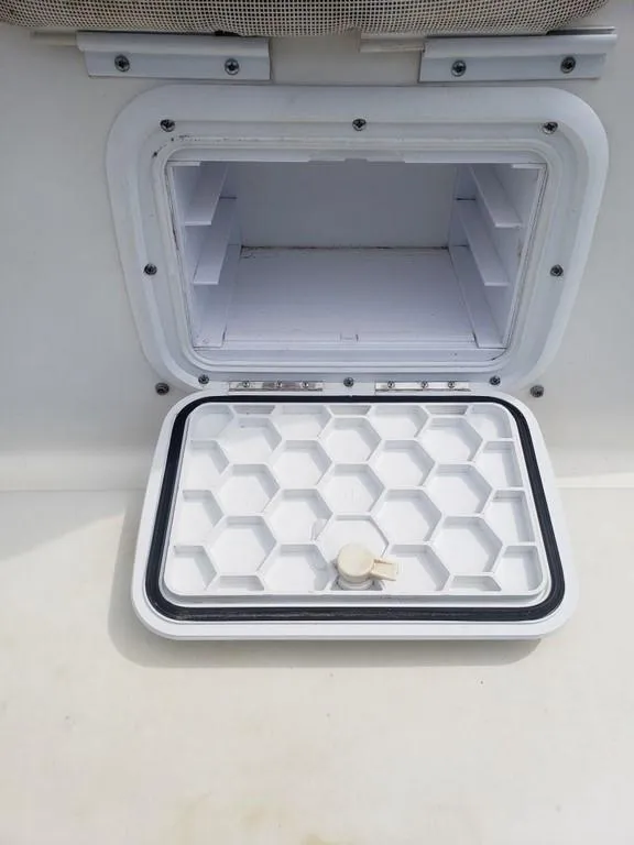 Slide: The Image of Open storage compartment on a 2008 Caracal 180 boat, featuring a hexagonal pattern lid. - 15