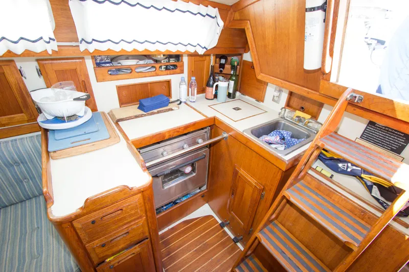 Slide: The Image of 1987 Ericson Mk III sloop interior with wooden cabinetry and compact kitchen area. - 5