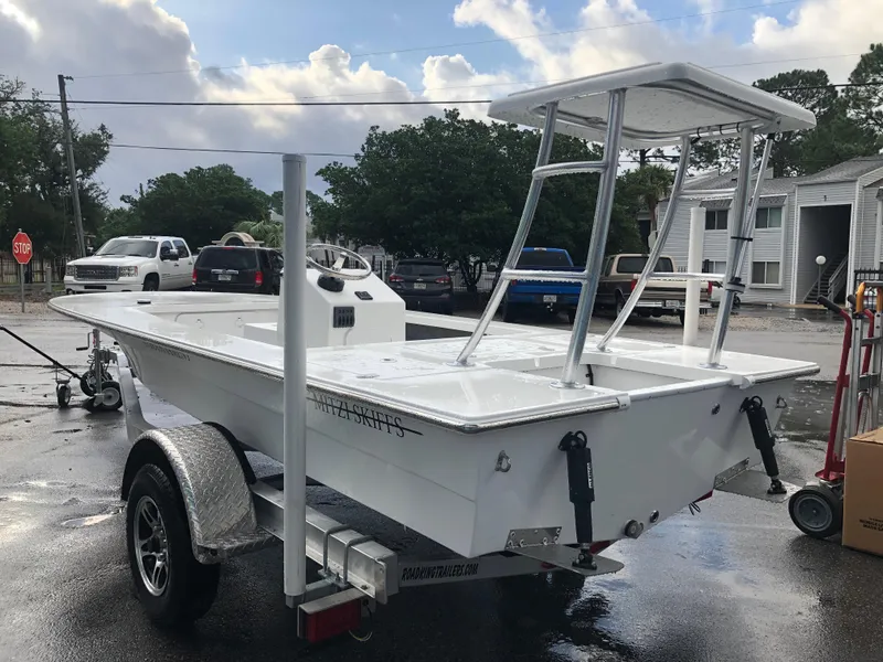 Slide: The Image of 2025 Mitzi Skiffs 17 boat on trailer, parked outdoors on a wet surface. - 1