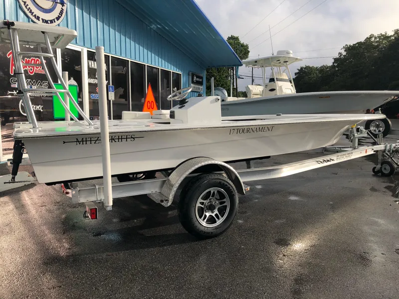 Slide: The Image of 2025 Mitzi Skiffs 17 boat on trailer, parked outside a blue building. - 15