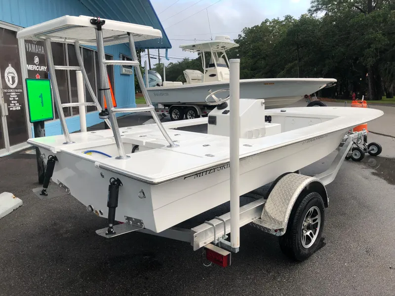 Slide: The Image of 2025 Mitzi Skiffs 17 boat on trailer, parked outdoors near a blue building. - 3