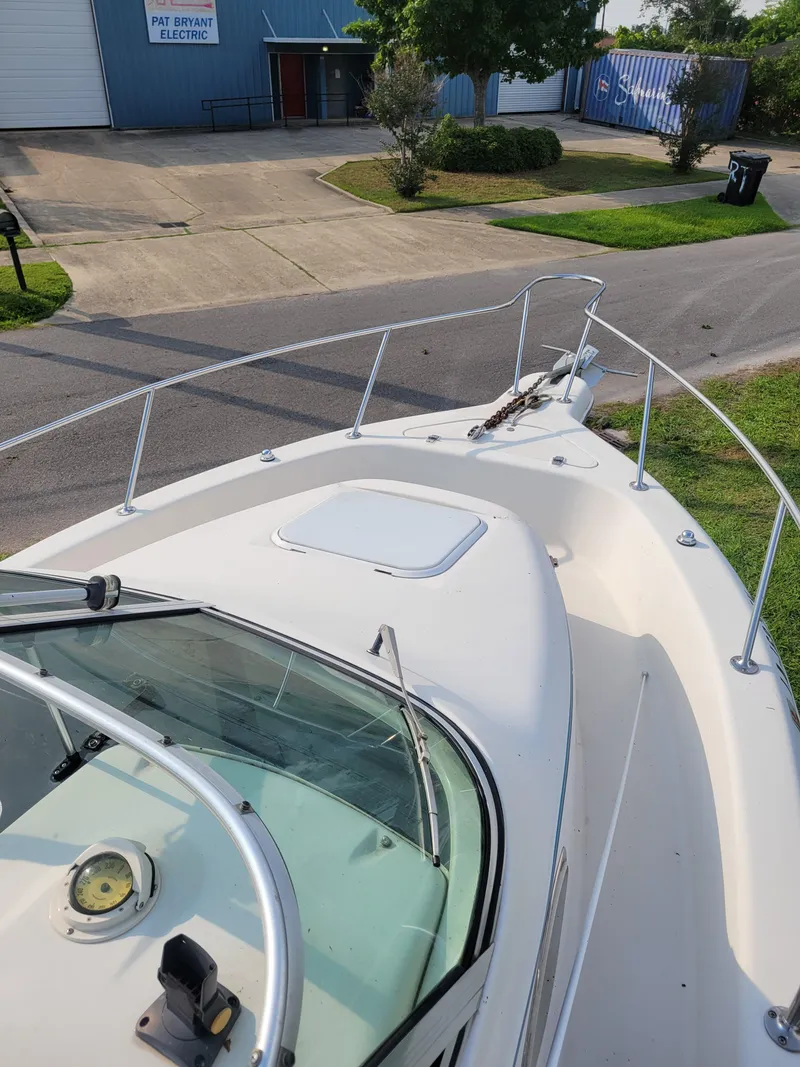 Slide: The Image of 1996 Pro-Line 231 Walk Around Cuddy boat docked near a warehouse. - 15