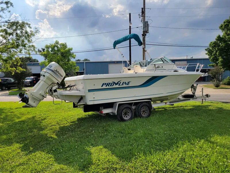 Slide: The Image of 1996 Pro-Line 231 Walk Around Cuddy boat on trailer, parked on grass. - 3