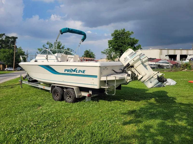 Slide: The Image of 1996 Pro-Line 231 Walk Around Cuddy boat on a trailer in a grassy area. - 5