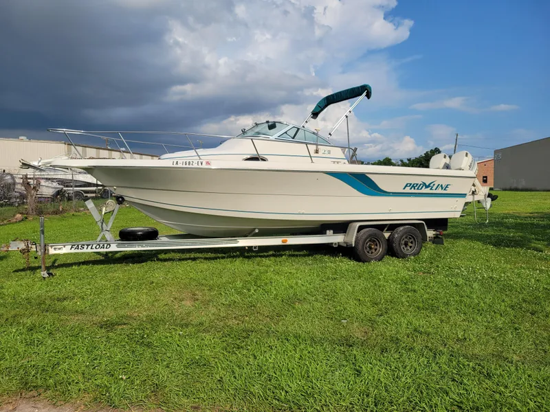 Slide: The Image of 1996 Pro-Line 231 Walk Around Cuddy boat on Fastload trailer, parked on grass. - 7