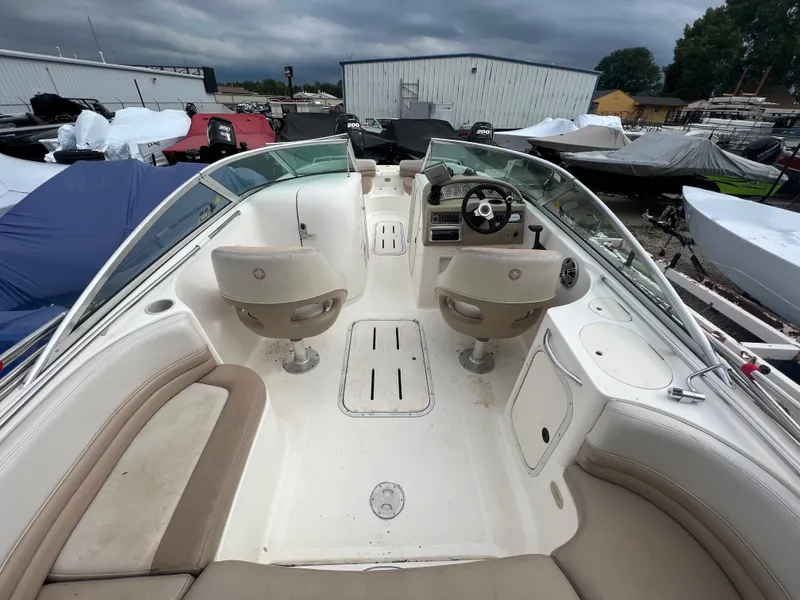 Slide: The Image of 2004 Bryant 234 boat interior with dual captain chairs and beige seating. - 8