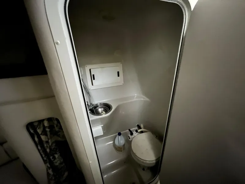 Slide: The Image of Compact bathroom in a 2000 Crownline 242 CR boat, featuring a toilet and sink. - 17