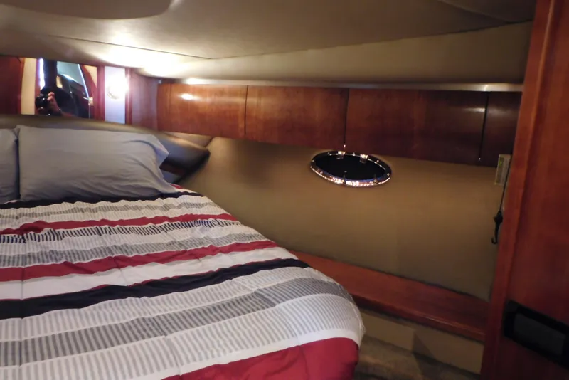 Slide: The Image of 2005 Cruisers Yachts 520 Express cabin with bed, wood paneling, and porthole window. - 29