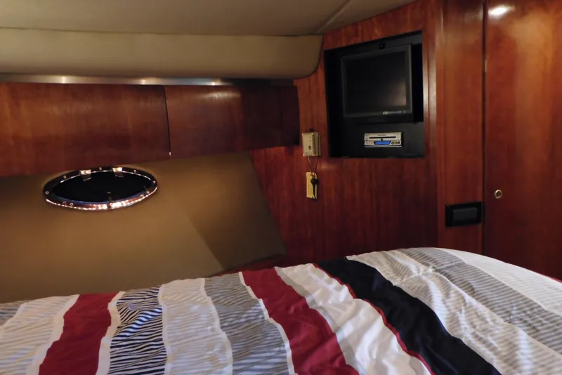 Slide: The Image of 2005 Cruisers Yachts 520 Express cabin interior with bed, TV, and wood paneling. - 32