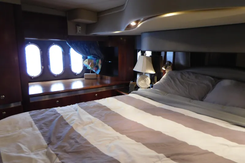 Slide: The Image of Luxurious bedroom interior of 2005 Cruisers Yachts 520 Express with striped bedding and porthole windows. - 42