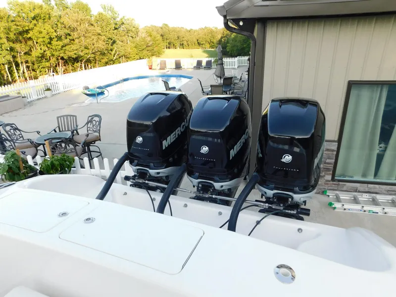 Slide: The Image of Three Mercury outboard motors on a 2005 Solid Craft LIMITED 40 boat near a poolside patio. - 28