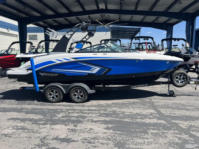 Slide: The Image of 2019 Chaparral Vortex 223 VRX boat in blue and white, parked on a trailer. - 0