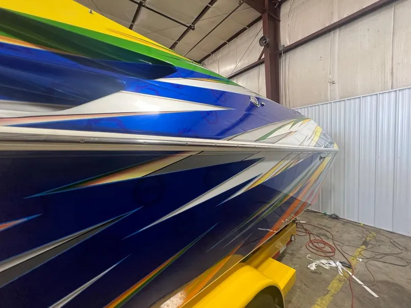 Slide: The Image of 2007 Fountain 42 Lightning boat with vibrant blue and yellow graphics in a warehouse. - 5