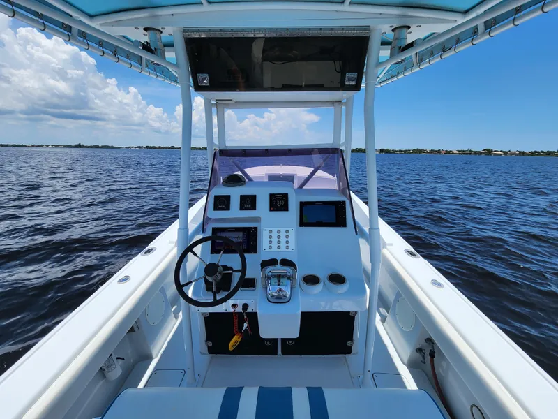 Slide: The Image of 1990 Intrepid 321 Cuddy boat helm with steering wheel and controls on open water. - 4