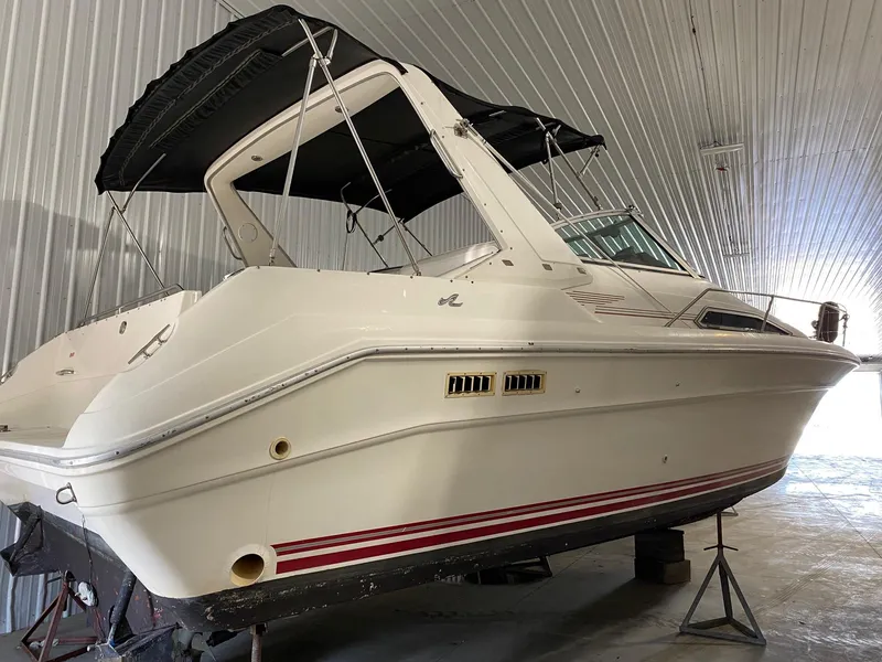 The Image of 1990 Sea Ray Sundancer boat in storage, white hull with red stripes. - 0