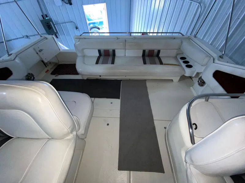 Slide: The Image of Interior of a 1990 Sea Ray Sundancer boat with white seating and striped cushions. - 10
