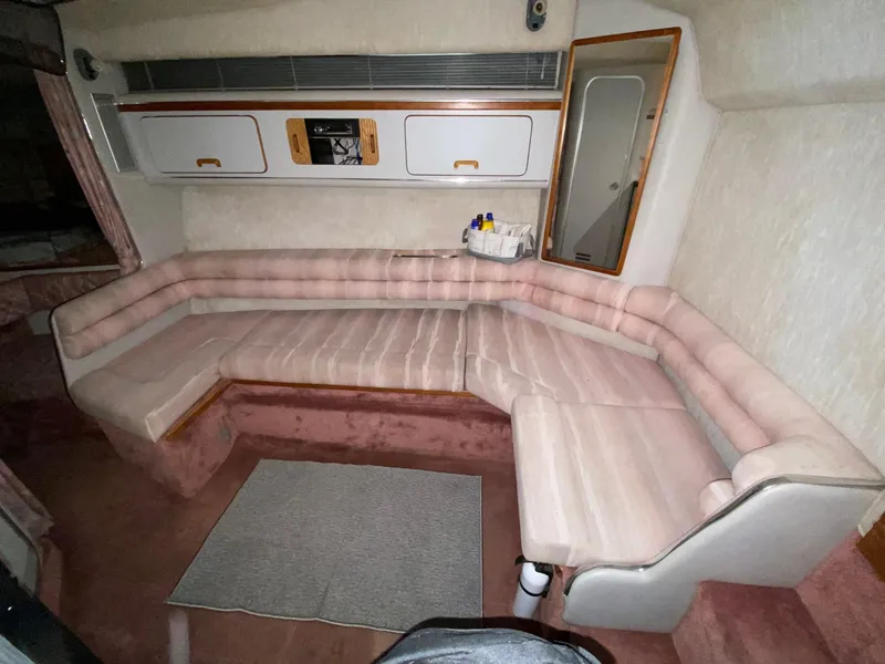 Slide: The Image of 1990 Sea Ray Sundancer interior with pink cushioned seating and storage cabinets. - 5