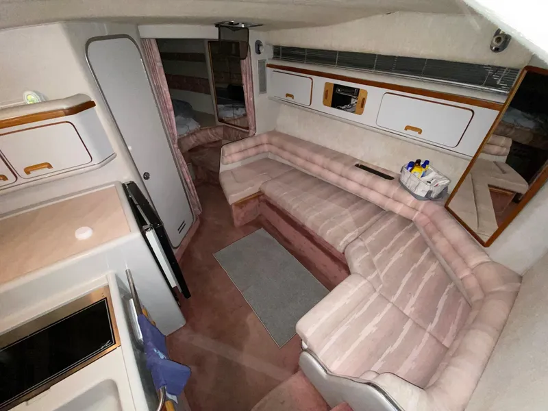 Slide: The Image of 1990 Sea Ray Sundancer cabin interior with pink seating, kitchenette, and storage cabinets. - 7