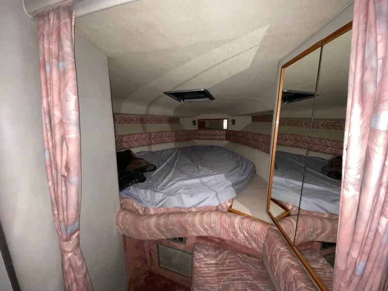 Slide: The Image of 1990 Sea Ray Sundancer cabin interior with bed, mirror, and pink curtains. - 8