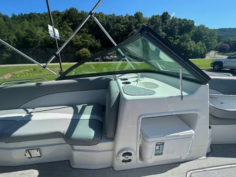 Slide: The Image of 2022 NauticStar 203DC Sport Deck boat interior with seating and console, set against a lush green backdrop. - 5
