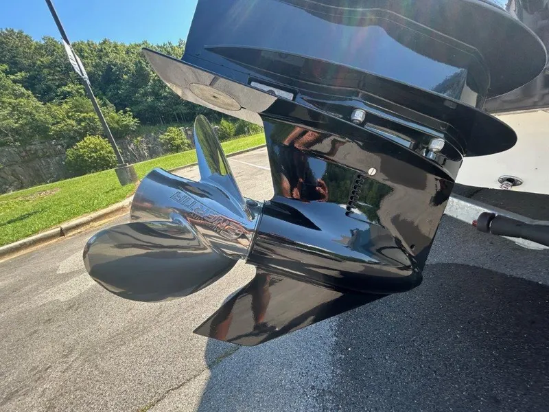 Slide: The Image of 2022 NauticStar 203DC Sport Deck boat propeller, shiny and reflective, in a sunny outdoor setting. - 9