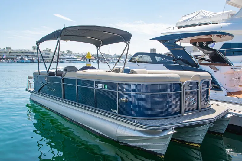 Slide: The Image of 2021 Manitou Oasis SHP pontoon boat docked in a marina, featuring a sleek design and canopy. - 32
