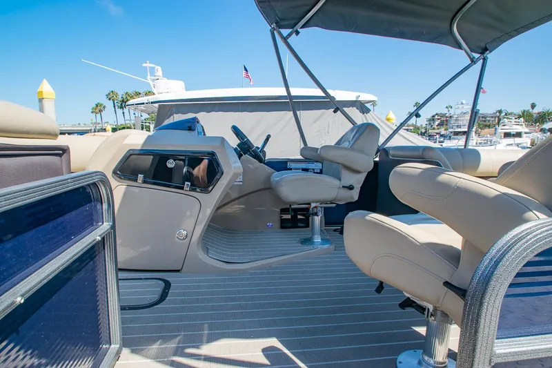 Slide: The Image of 2021 Manitou Oasis SHP pontoon boat interior with helm and seating under canopy. - 38