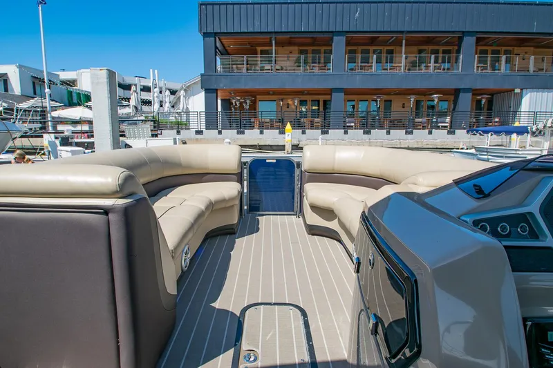 Slide: The Image of 2021 Manitou Oasis SHP pontoon boat with spacious seating, docked near a modern building. - 39