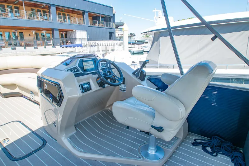 Slide: The Image of 2021 Manitou Oasis SHP boat interior with helm, steering wheel, and captain's chair. - 48