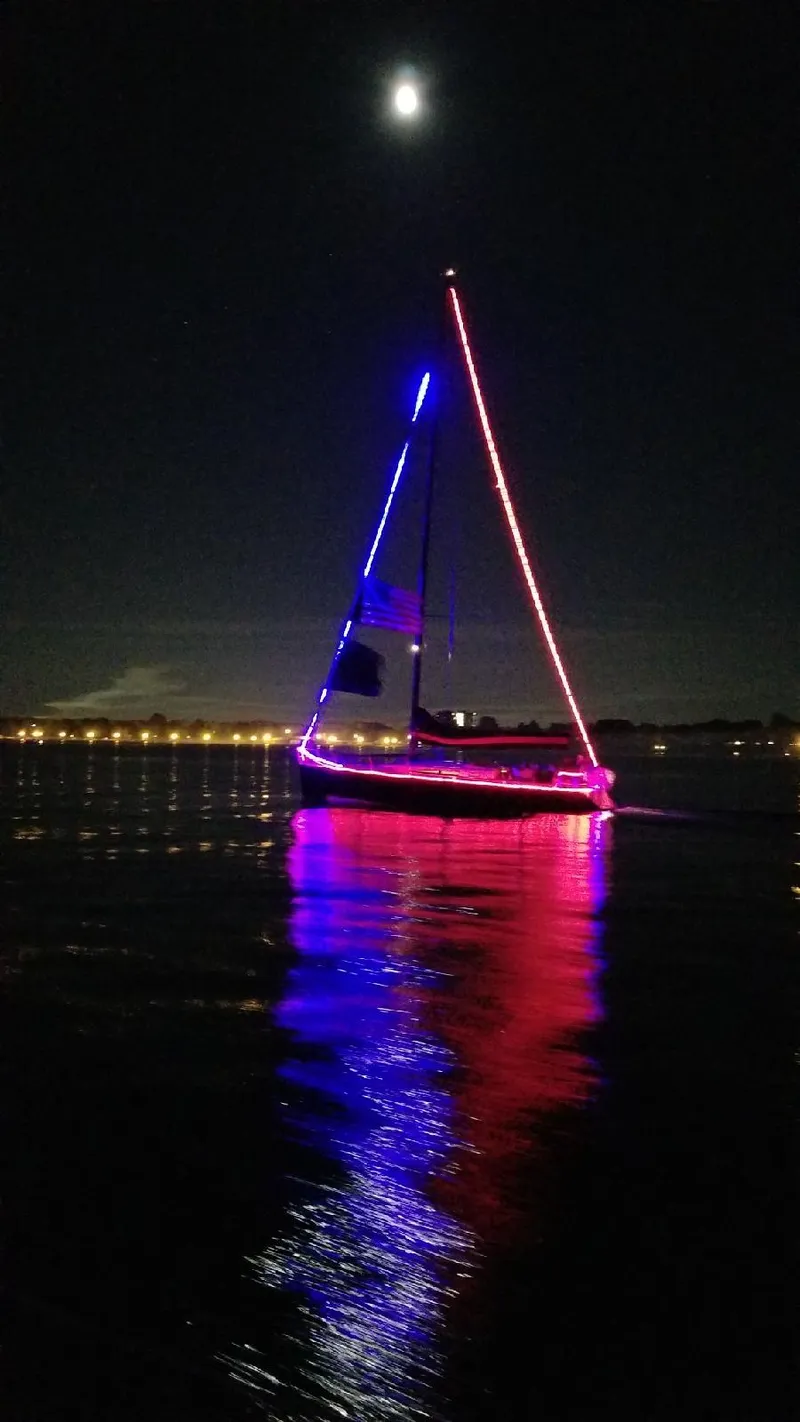 Slide: The Image of A lit-up sailboat on the water at night, featuring colorful lights and moonlight. - 34