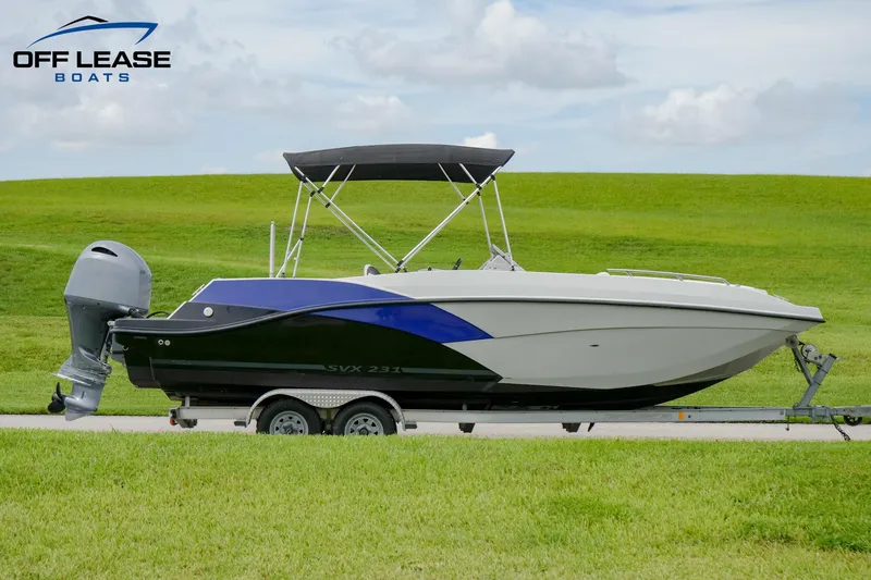 Slide: The Image of 2022 Starcraft SVX 231 OB boat on a trailer with a green field background. - 1