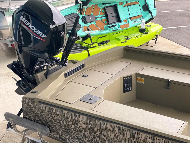 Slide: The Image of 2023 Thor 1860 boat with Mercury engine, parked beside a vibrant kayak. - 6