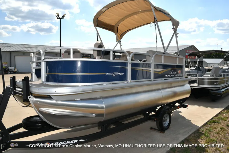 Slide: The Image of 2025 Sun Tracker Bass Buggy 16 XL Select pontoon boat on trailer, outdoor display. - 13